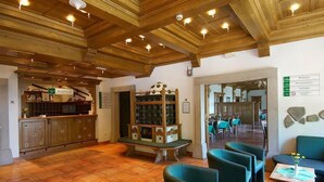 A restaurant with wooden ceiling beams, a reception desk, and a wine display. - Hotel Tisa (Hoce-Slivnica)