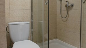 Un baño moderno con inodoro, cabina de ducha con paredes de vidrio y bañera.
