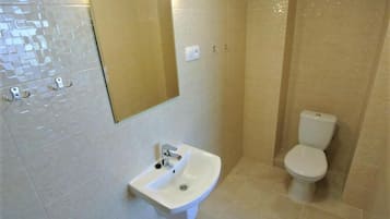 Een badkamer met een wit wastafel, een spiegel en een toilet.