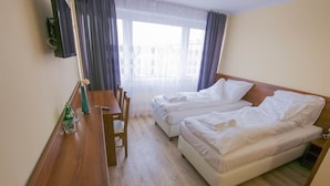 Habitación de hotel con dos camas, un escritorio de madera y un ventanal con cortinas.