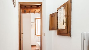 A hallway with a wooden door leading to a room, a radiator, and a wooden cabinet with a lace curtain. - Chiasso degli Armati Apartment (Florence)