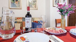 A dining table set with plates, a wine bottle, a pitcher, and a vase with flowers. - Chiasso degli Armati Apartment (Florence)