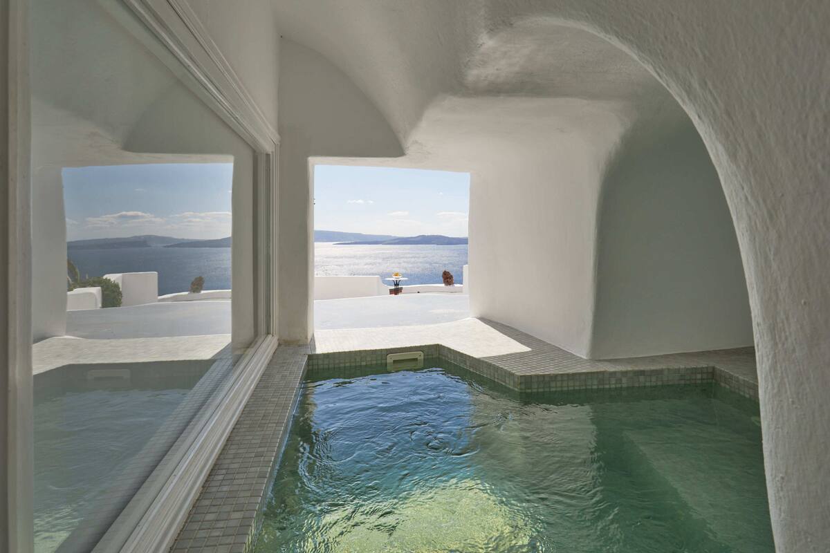Ein moderner, überdachter Pool mit Blick auf das Meer und die Berge.