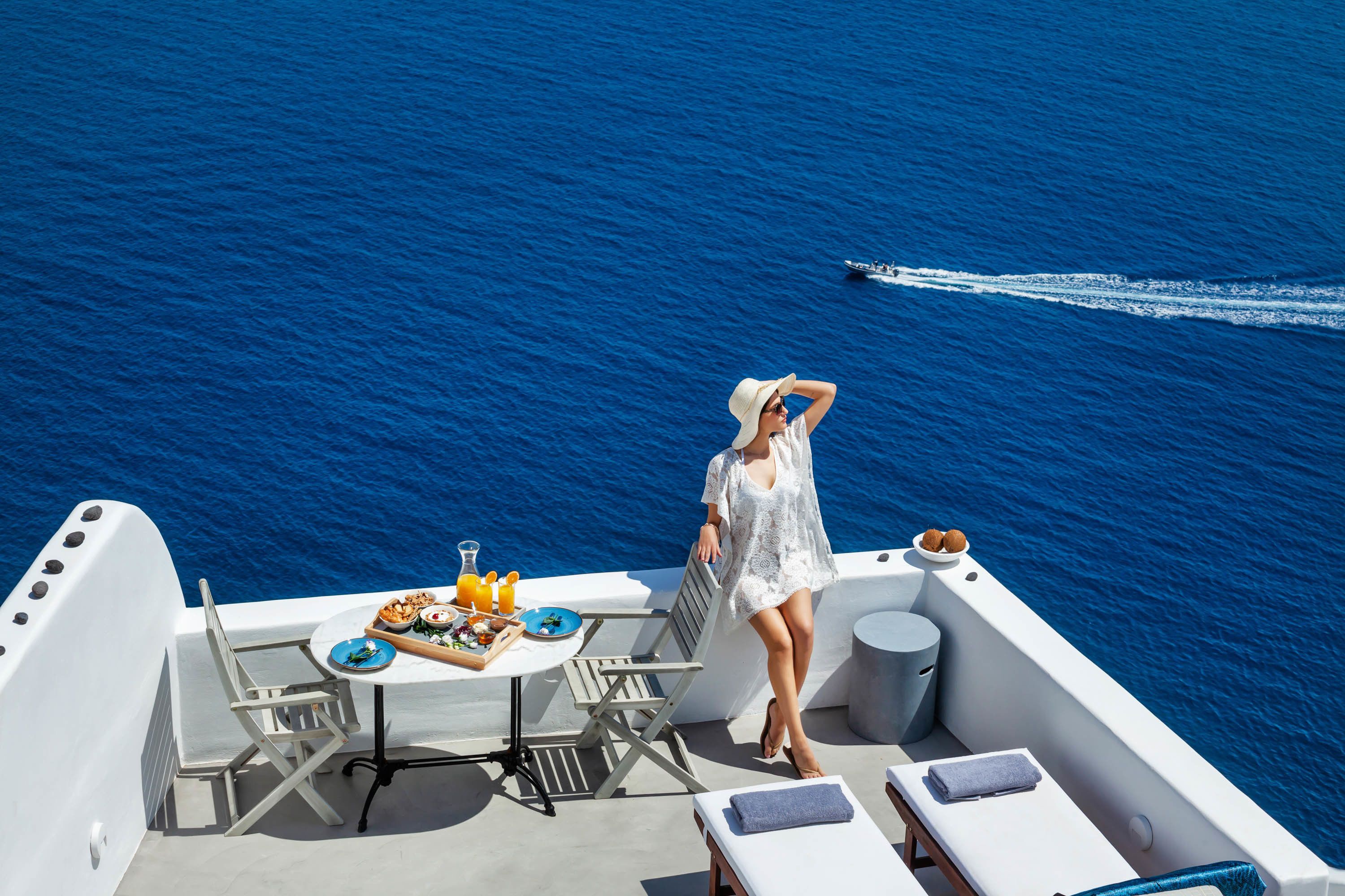 Un balcón con mesa lista para el desayuno, un área de estar y vista al mar.
