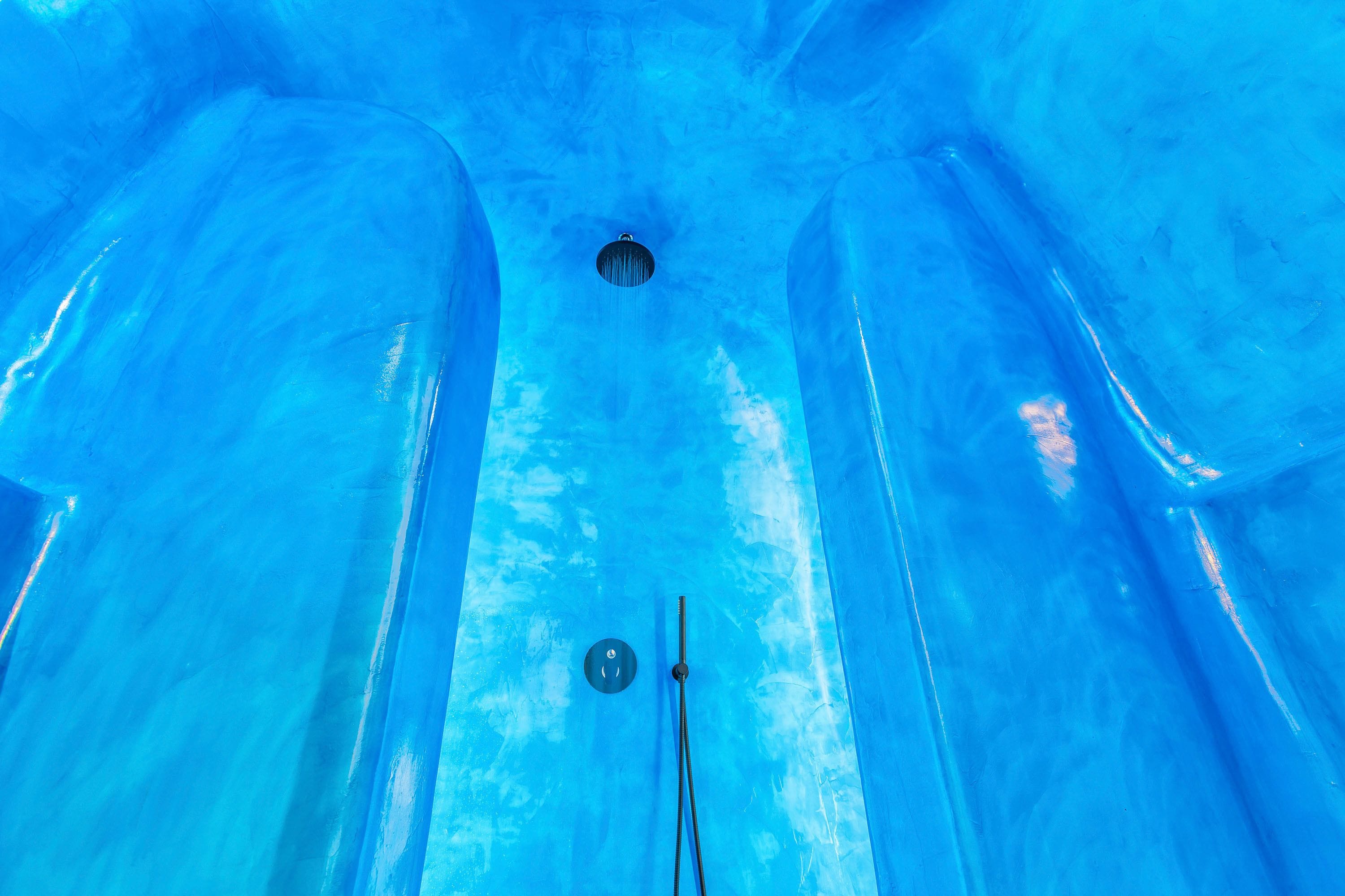 Una piscina de gel amb un desguàs central i dos desguassos més petits, envoltada per parets de gel llises i reflectants.