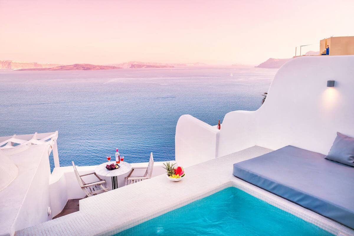 Ein Poolbereich mit Meerblick, ein Tisch mit Getränken und Früchten sowie eine Sitzecke.