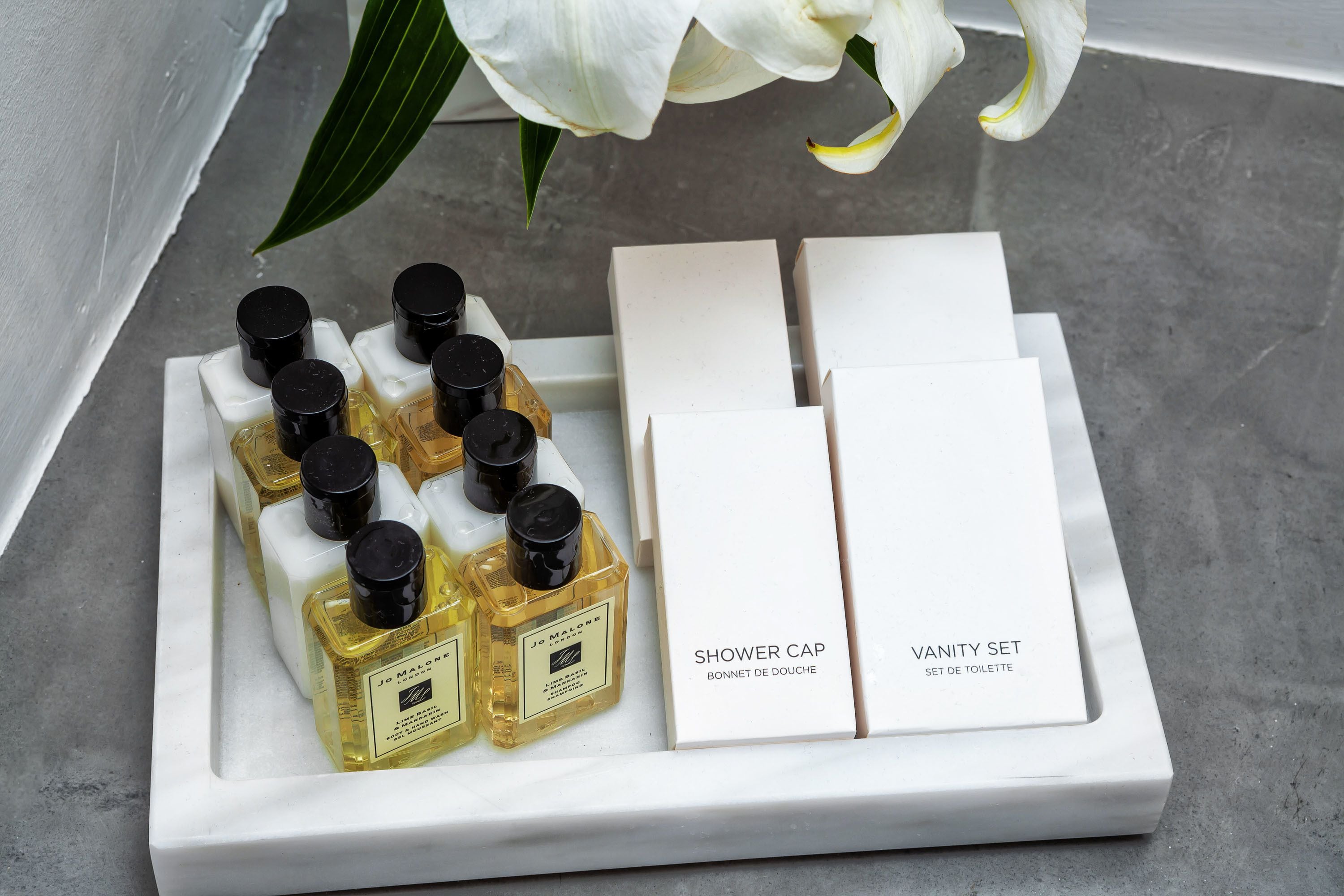 A tray with a set of shower caps and a vanity set, including a bottle of perfume.