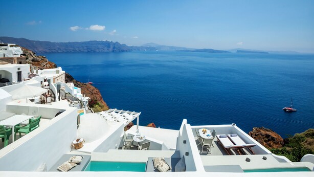 A seaside hotel with white architecture, a pool, and a view of the sea. - Diamond Luxury Suites Collection (Santorini)