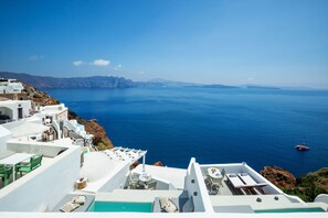 A seaside hotel with white architecture, a pool, and a view of the sea. - Diamond Luxury Suites Collection (Santorini)