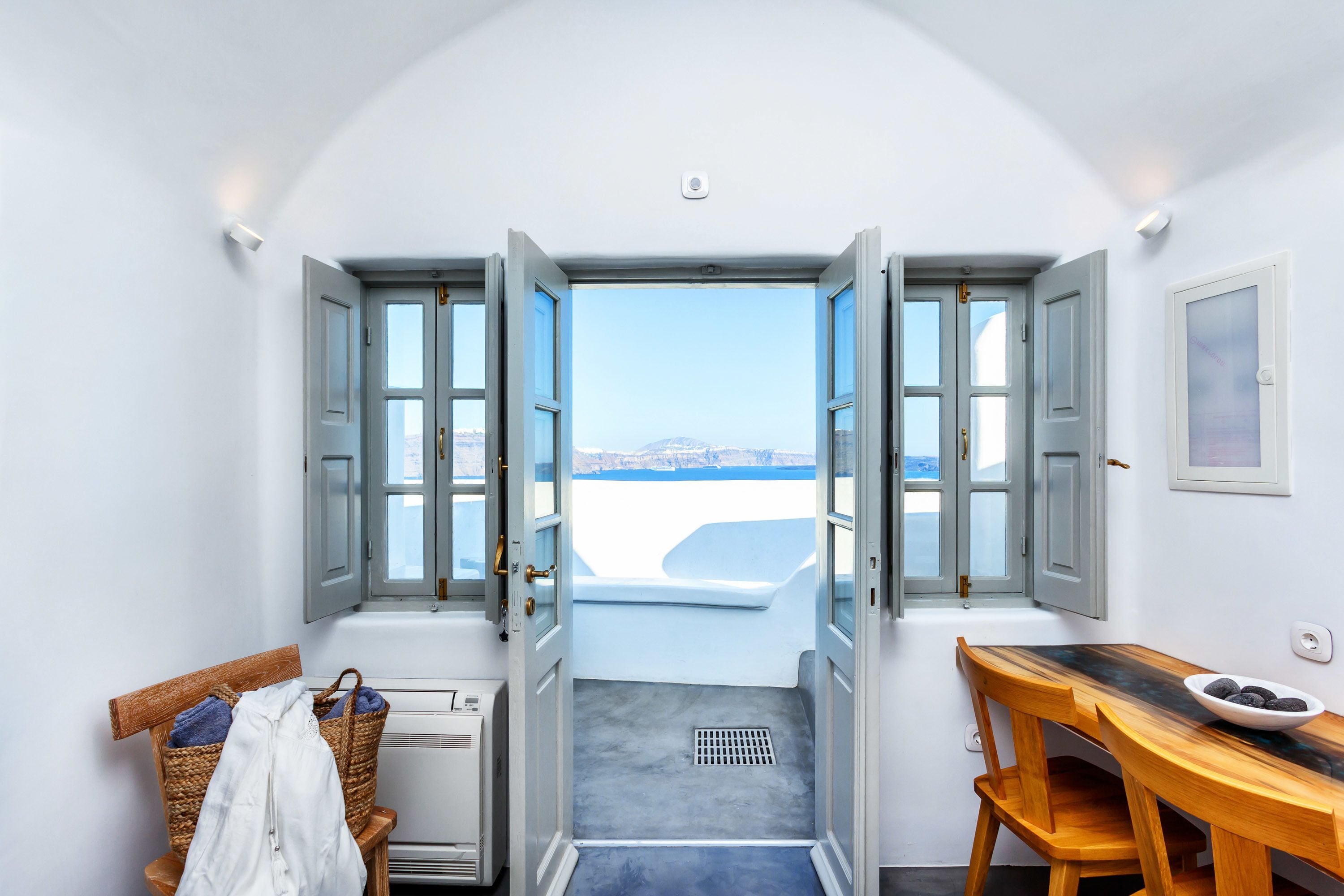 Una habitación con vistas al mar, una bañera, una mesa de madera y una silla de mimbre.