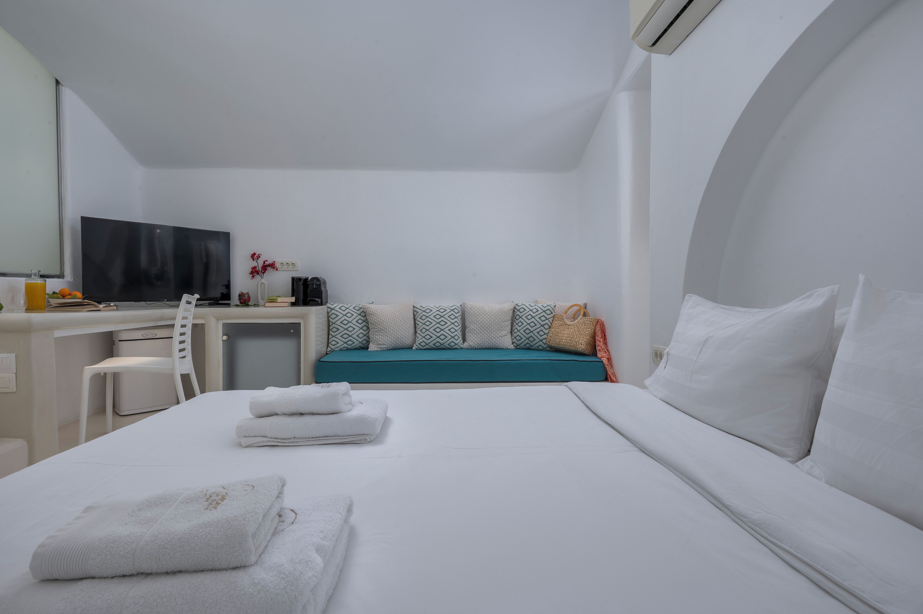 A hotel room with a bed, a desk, a chair, a TV, and a window.