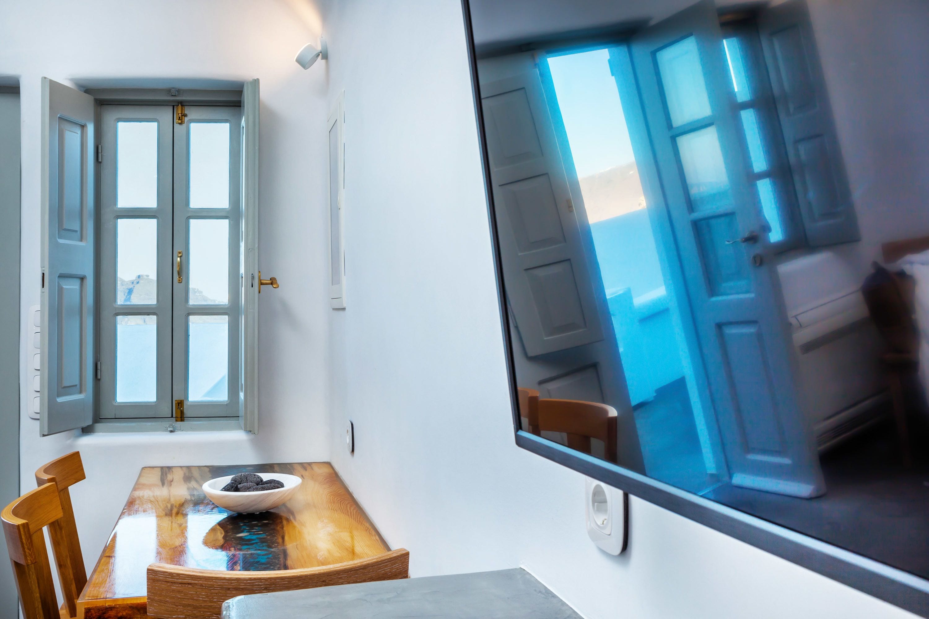 Un comedor con una mesa de madera, sillas y un cuenco. Hay un ventanal con vistas a una puerta y una silla afuera.
