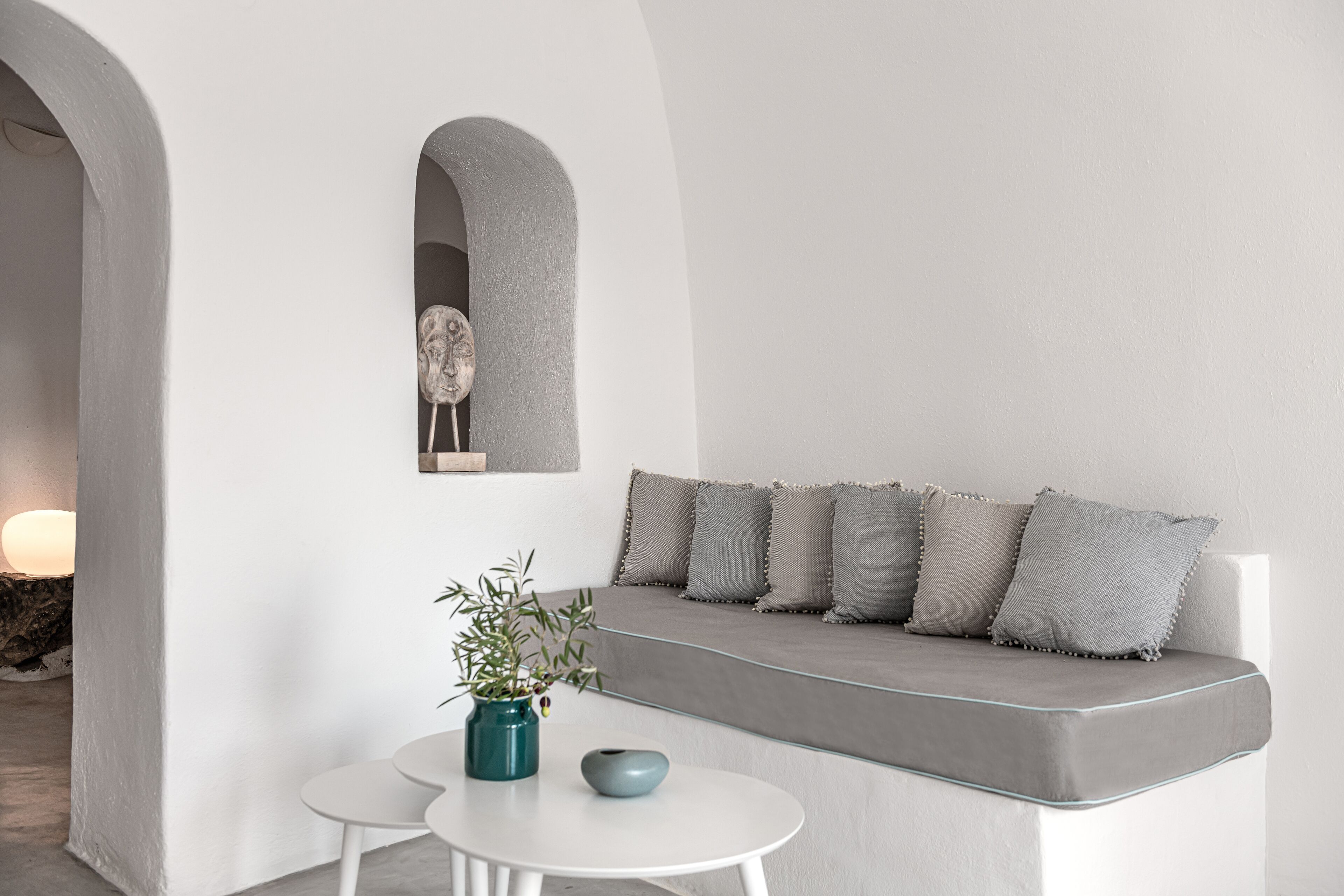 A minimalist interior with a white sofa, a small table, and a decorative vase.