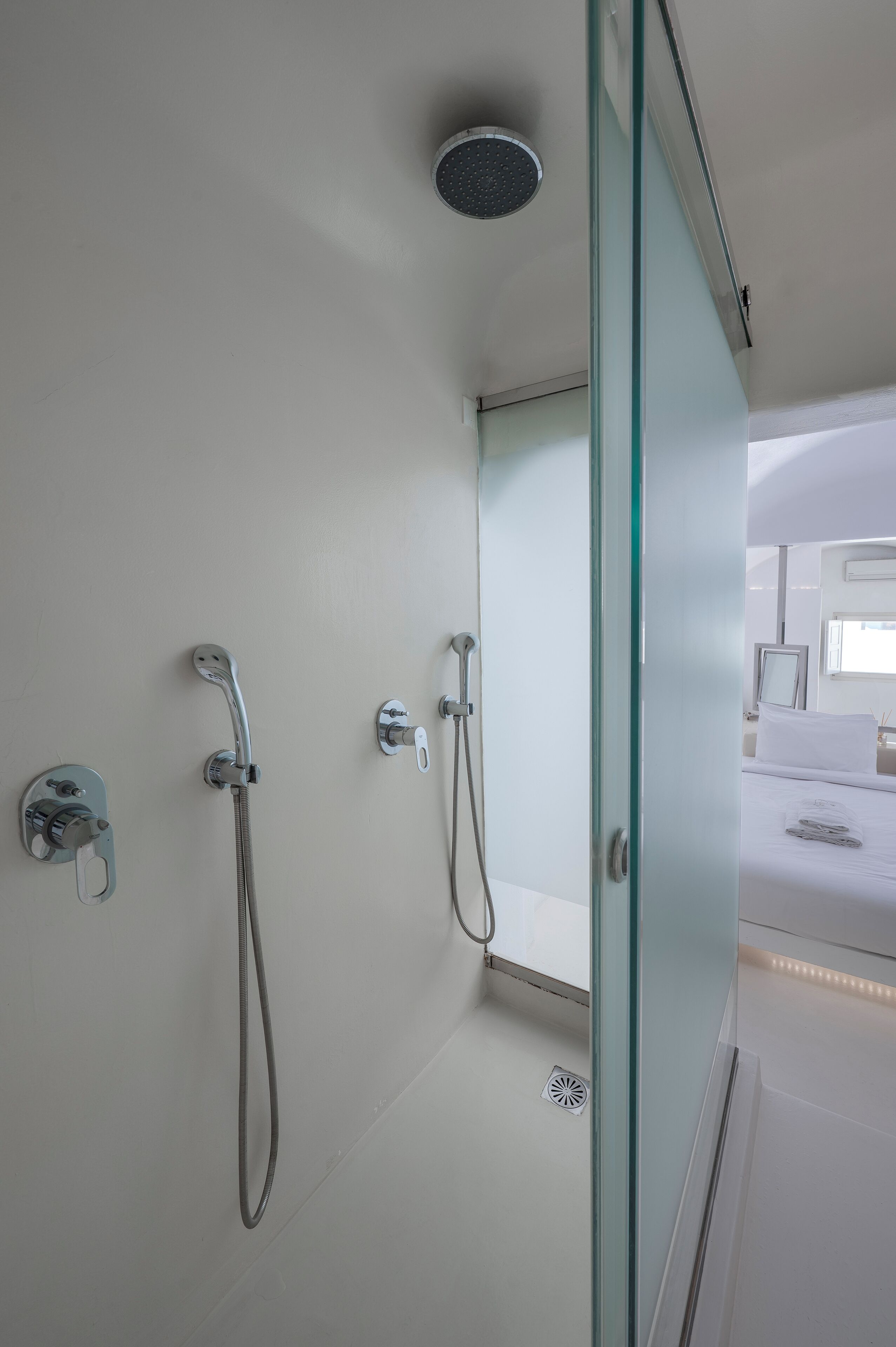 A modern bathroom with a glass shower enclosure, a handheld showerhead, and a wall-mounted faucet.