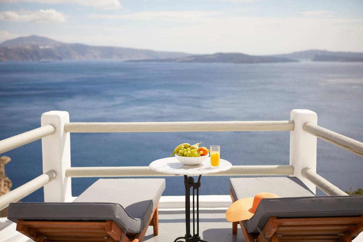 Ein Balkon mit einem Frühstückstisch, der einen malerischen Blick auf das Meer und das entfernte Land bietet.