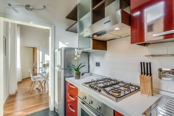 A modern kitchen with stainless steel appliances, a gas stove, and wooden cabinets. - Apartments Florence - Luna Chic (Firenze)