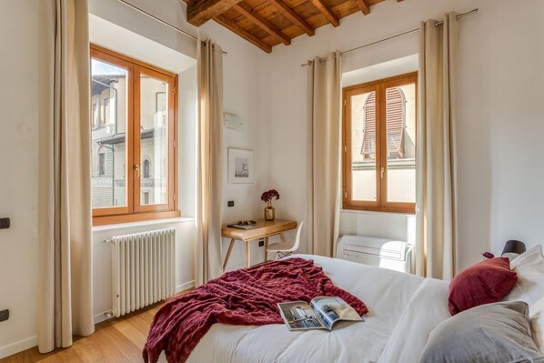Un dormitorio con cama, escritorio, silla y radiador.