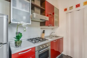 A kitchen with a gas stove, oven, sink, and red cabinets.