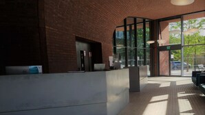 A reception area with a modern design, featuring a reception desk, seating area, and large windows allowing natural light.