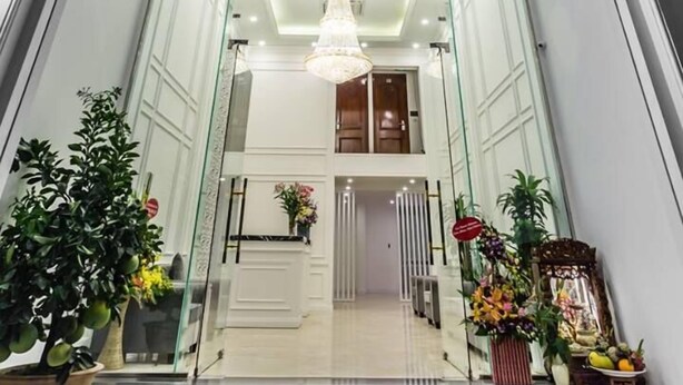 The entrance of A83 Hotel Hanoi with a modern design, featuring a glass facade, a chandelier, and potted plants. - Hanoi A83 Hotel (Hanoi)
