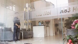A hotel reception area with a glass facade, a reception desk, and a seating area with sofas. - Hanoi A83 Hotel (Hanoi)