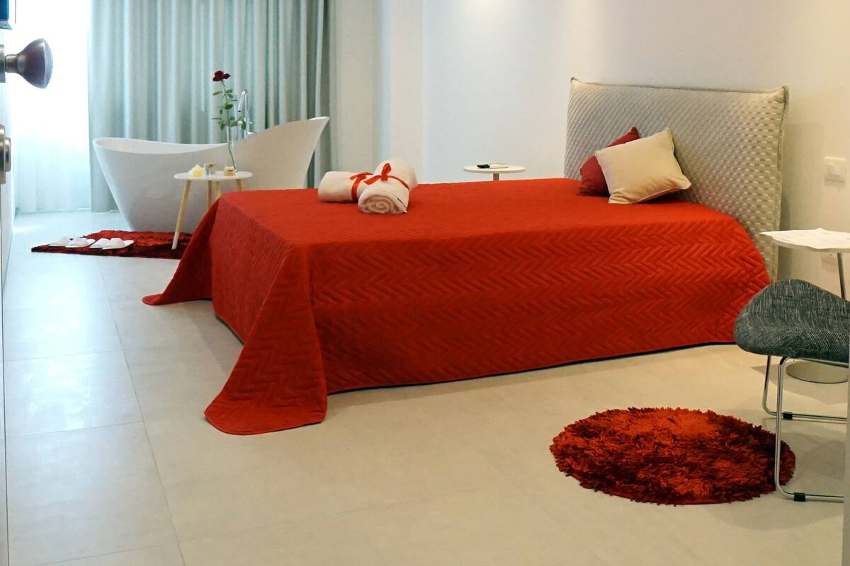 Ein modernes Hotelzimmer mit einem großen Bett, einer Sitzecke und einer Badewanne.