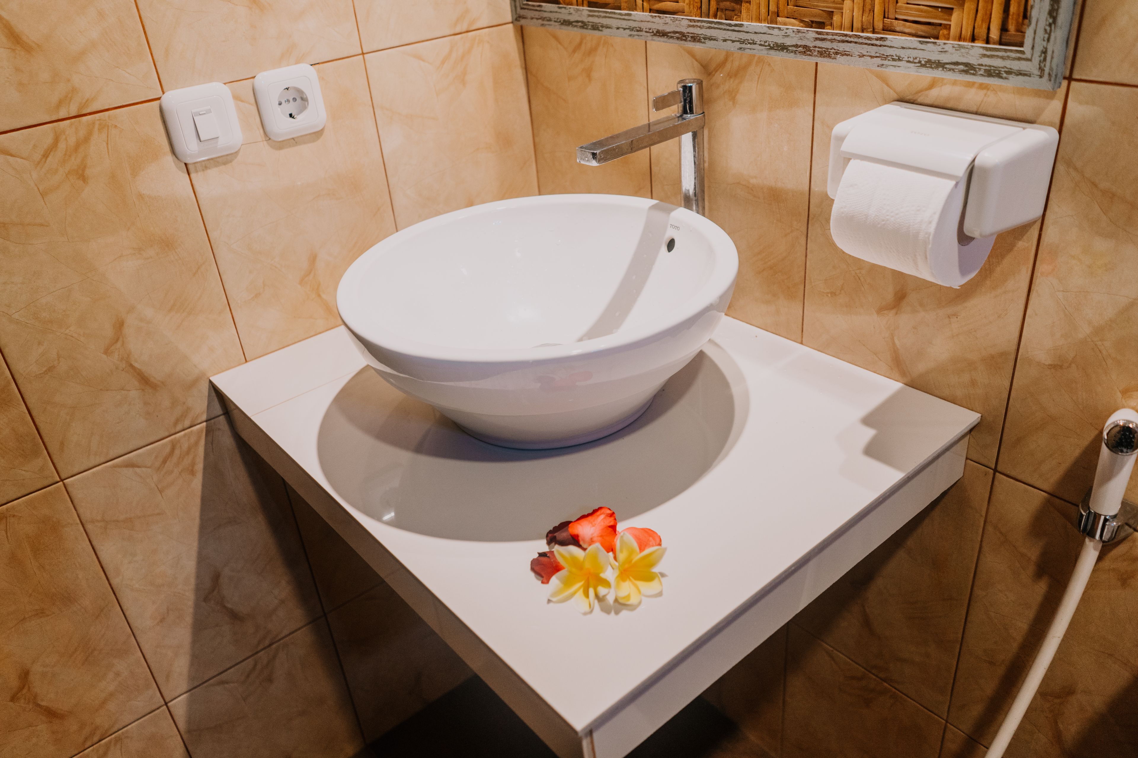 Un bagno con un lavandino bianco, uno specchio e un porta carta igienica.