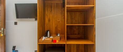 A wooden wardrobe with shelves, a small refrigerator, and a water dispenser.