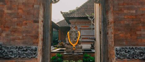 A traditional gate with intricate carvings, a small shrine with a statue, and a decorative overhead structure.