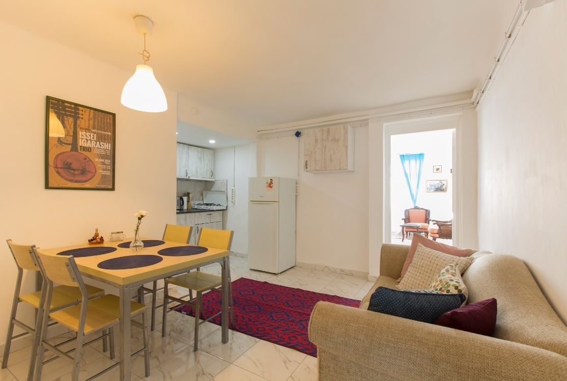 A compact living space with a dining area, kitchenette, and a sofa.
