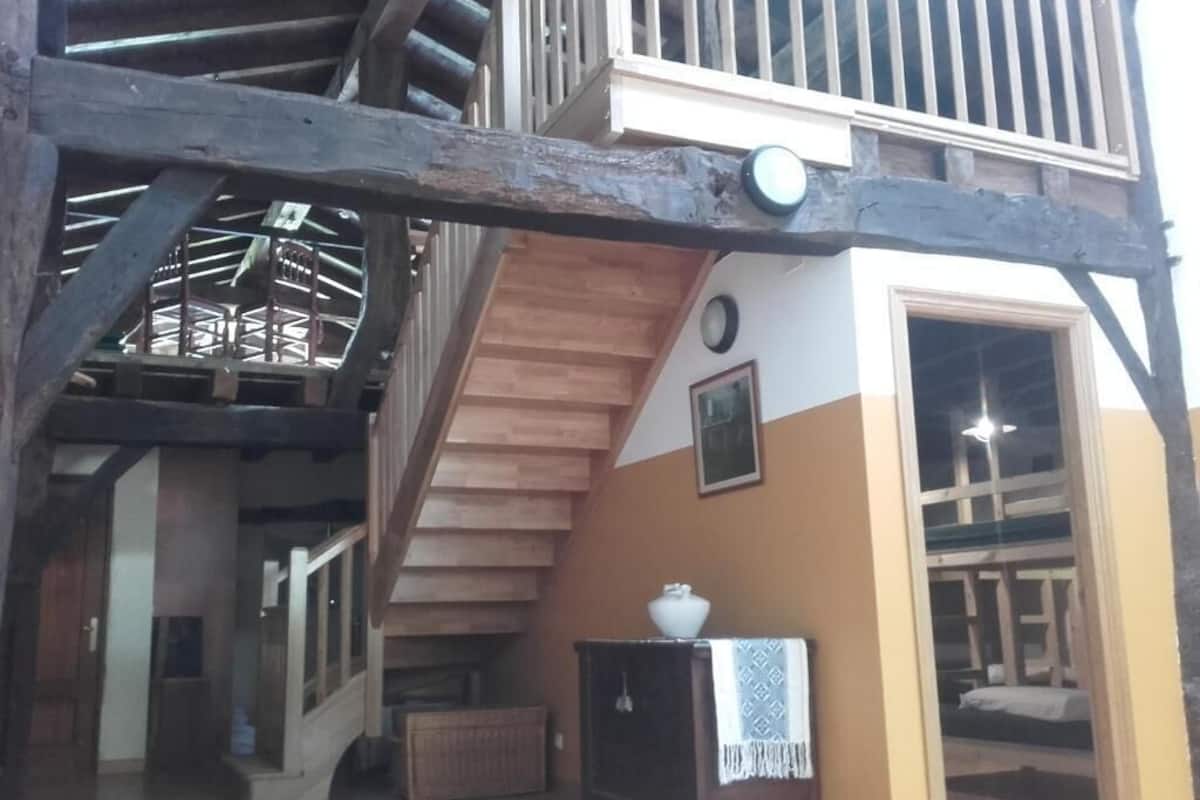 Une structure en bois à plusieurs niveaux, dotée d’un escalier, d’une petite table avec un bol, et d’une porte donnant sur une autre pièce.
