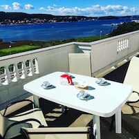 Una mesa para cuatro con vistas a un cuerpo de agua y colinas al fondo.