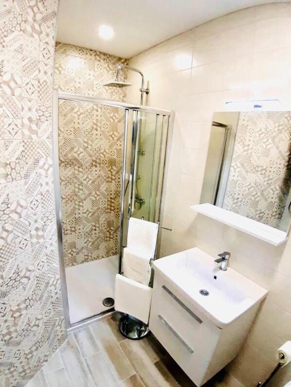 A modern bathroom with a shower, a sink, and a mirror.