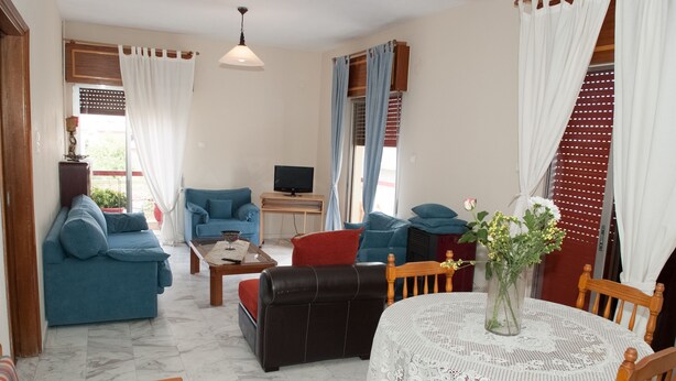 Una sala de estar con sofá, mesa de centro, televisor y mesa de comedor con sillas.