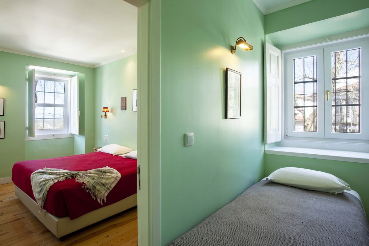 Een kamer met een bed, een raam en een wandlamp.