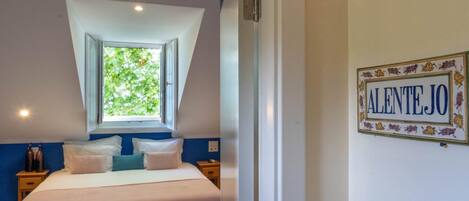 Un dormitorio con cama, ventana, mesita de noche y un cartel en la pared.