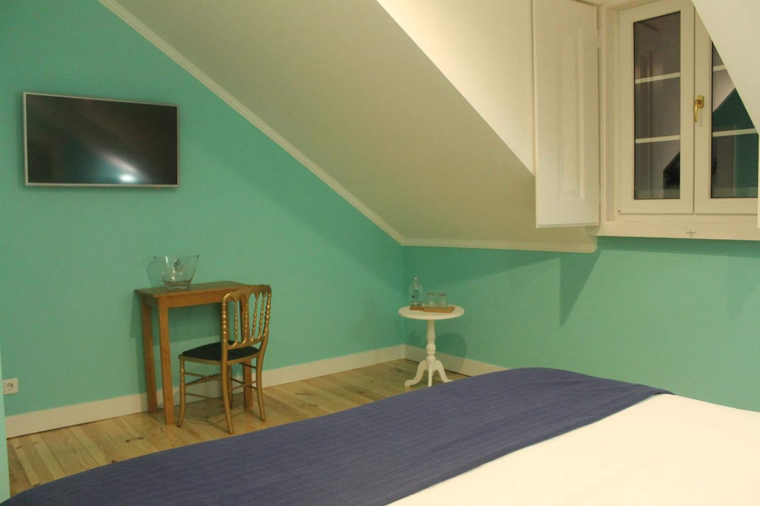 A room with a bed, a television, a small table, and a chair.