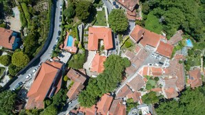 An aerial view of a residential area with red-tiled roofs, a swimming pool, and a curved road.