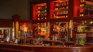 A bar area with multiple shelves of bottles, a variety of glasses, and a selection of spirits. - Waterford Castle Lodges (Waterford)