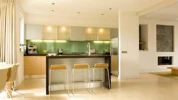 A modern kitchen with a central island, bar stools, and a dining area with a table and chairs.