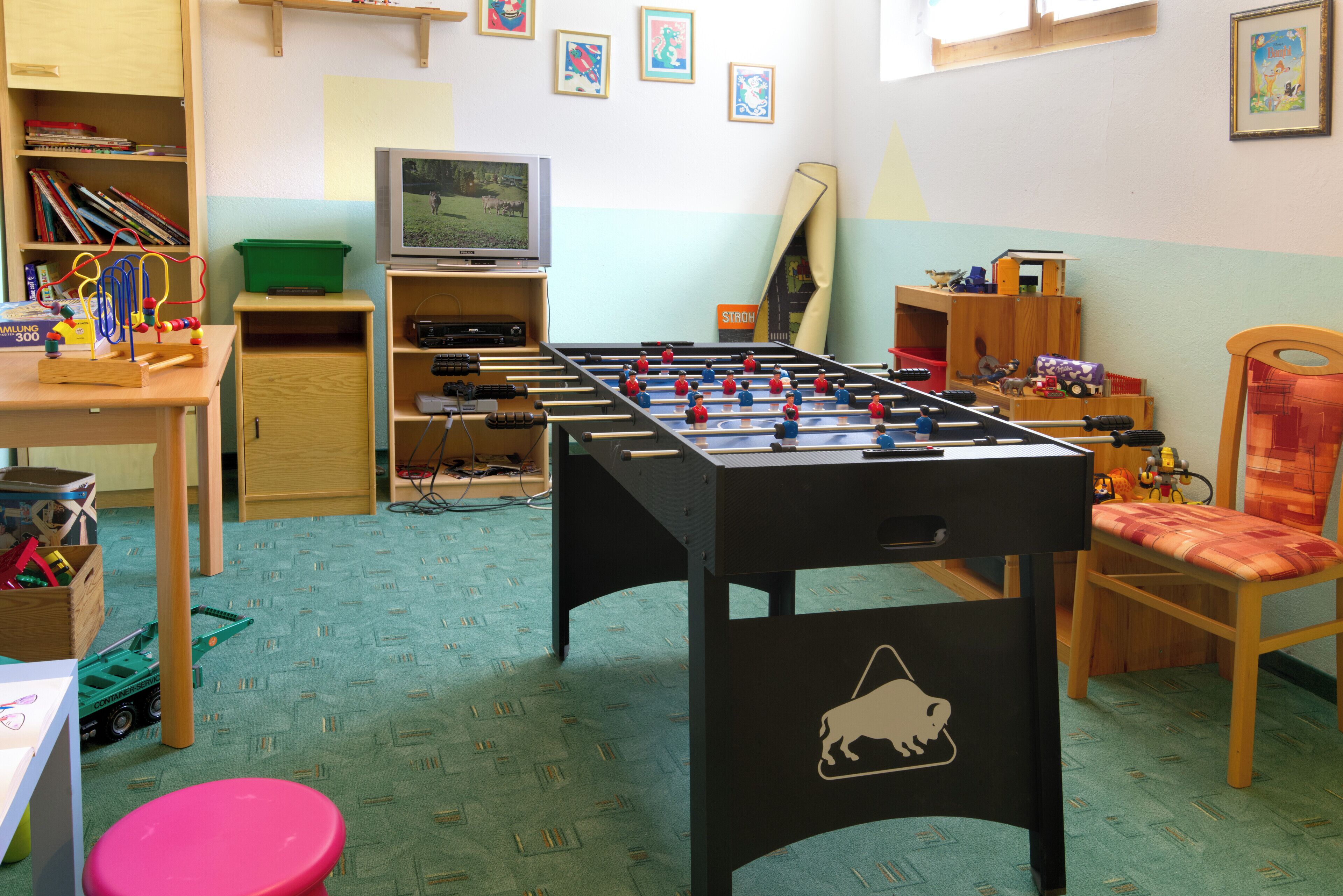 A room with a foosball table, a television, and various toys.