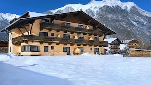 A multi-story hotel with balconies and a snow-covered mountain backdrop.