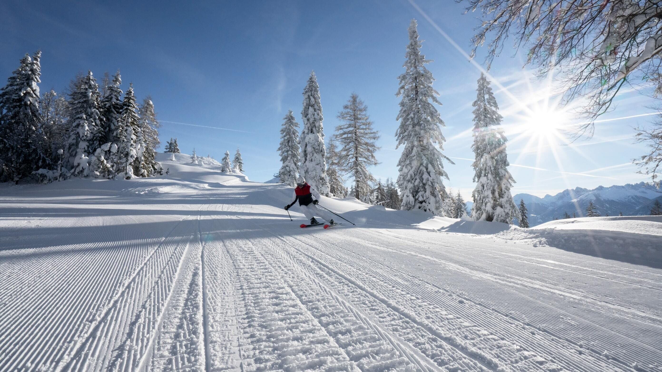 A snowy ski slope with a skier in motion.
