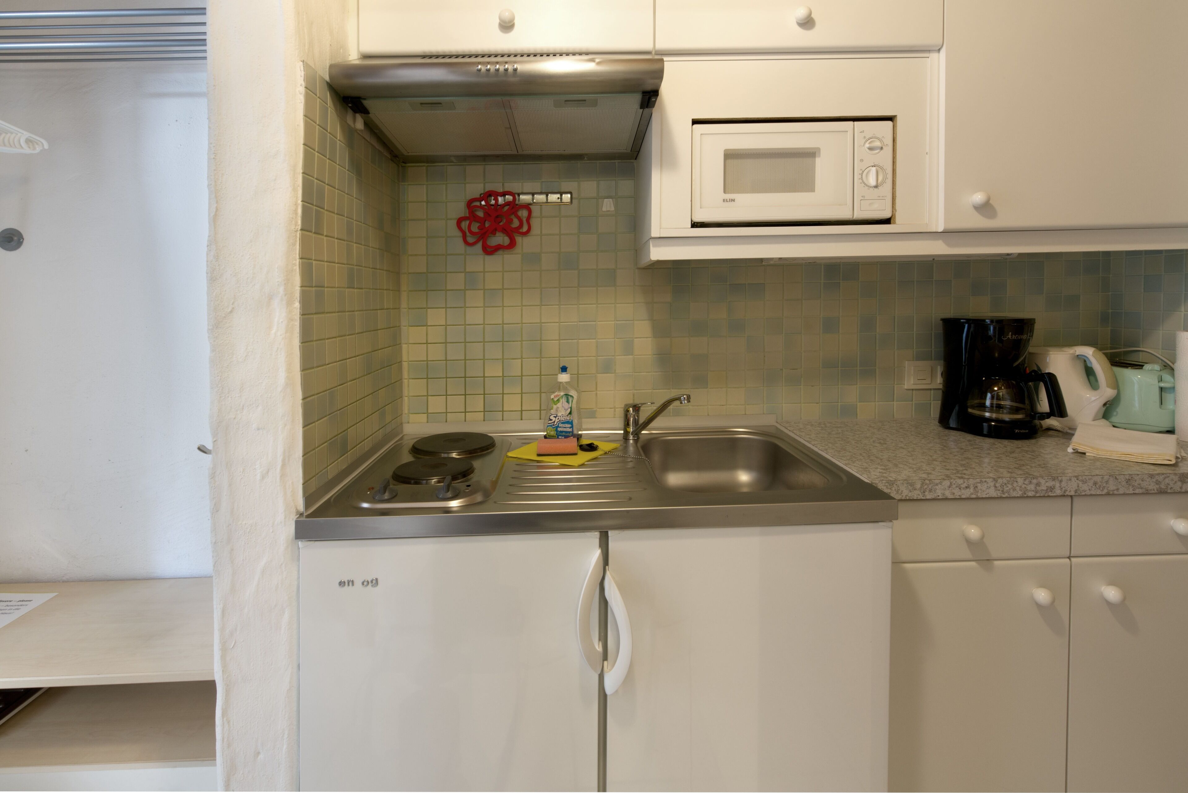 A compact kitchen with a microwave, sink, and coffee maker.