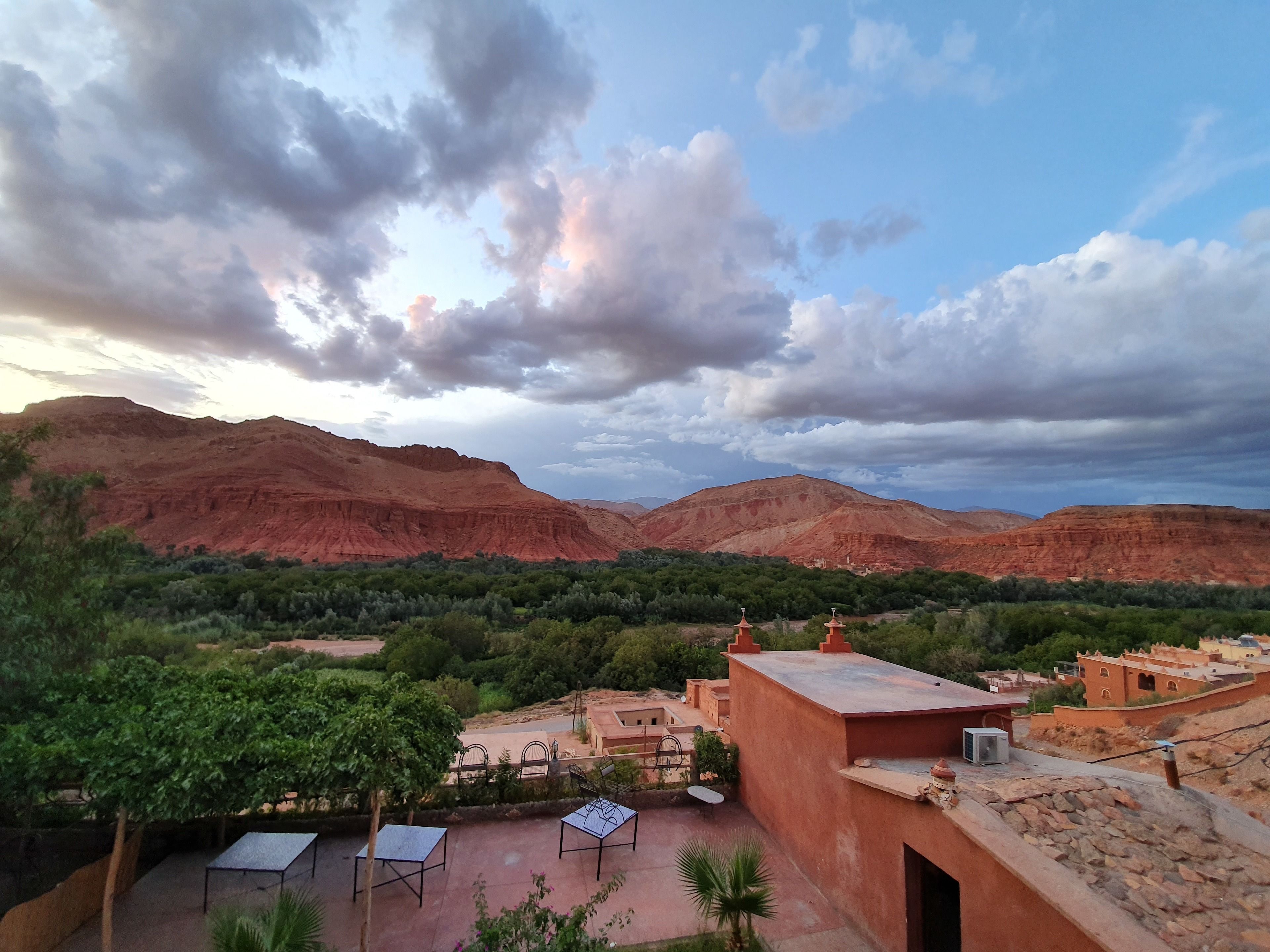 Un paisaje montañoso con vistas a edificios en terrazas y un patio con mesas y sillas.