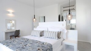 Ein modernes Schlafzimmer mit einem großen Bett, einem Schreibtisch und zwei Pendelleuchten.