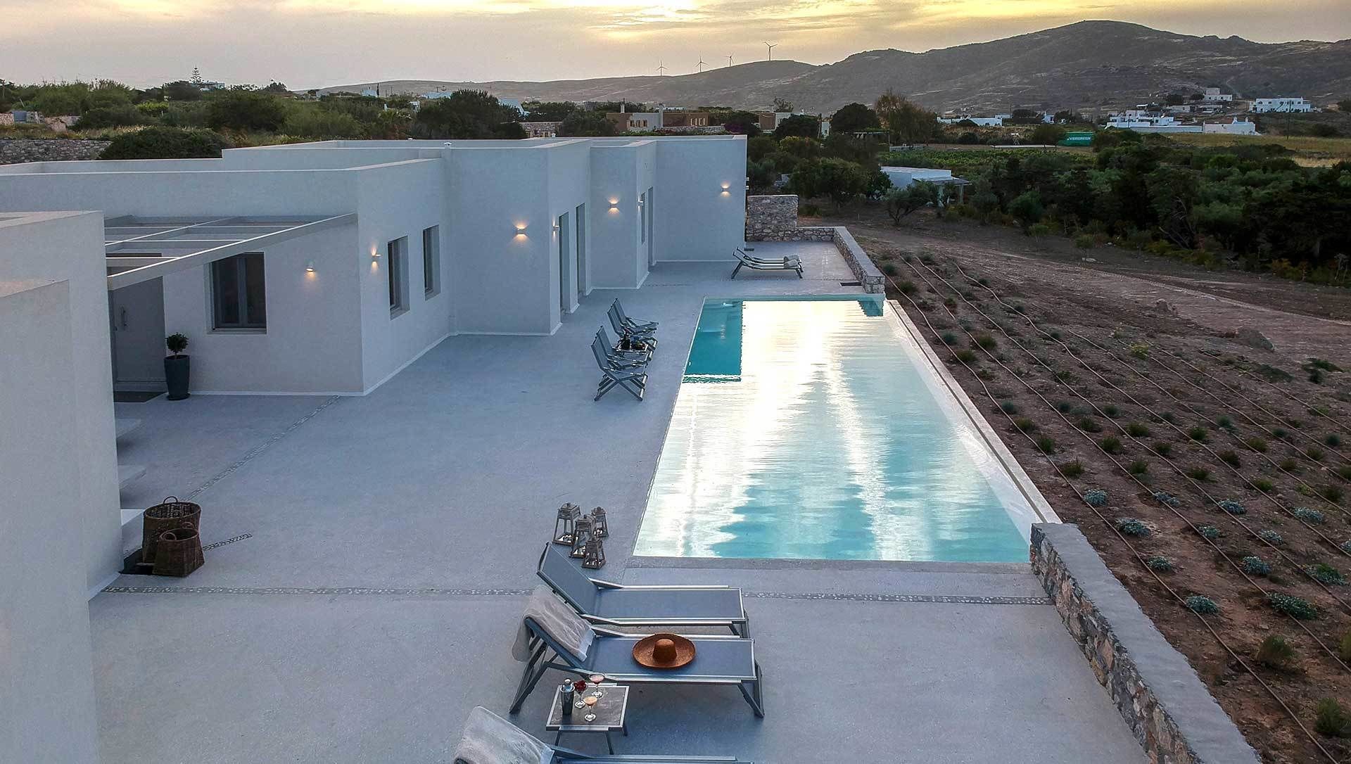 Un área de piscina exterior moderna con sillones de descanso y zona de comedor.