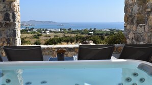 Ein Whirlpool mit Blick auf das Meer und eine Steinmauer.