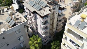 A multi-story residential building with balconies, satellite dishes, and solar panels. - Hisar Otel (Alanya)