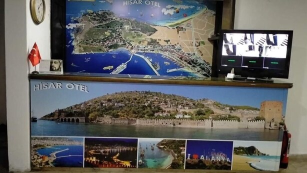 A reception desk with a large map of Alanya, a clock, and a television screen. - Hisar Otel (Alanya)
